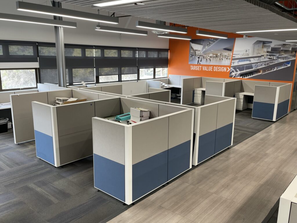 Modern office cubicles with blue and white panels in a spacious workspace.