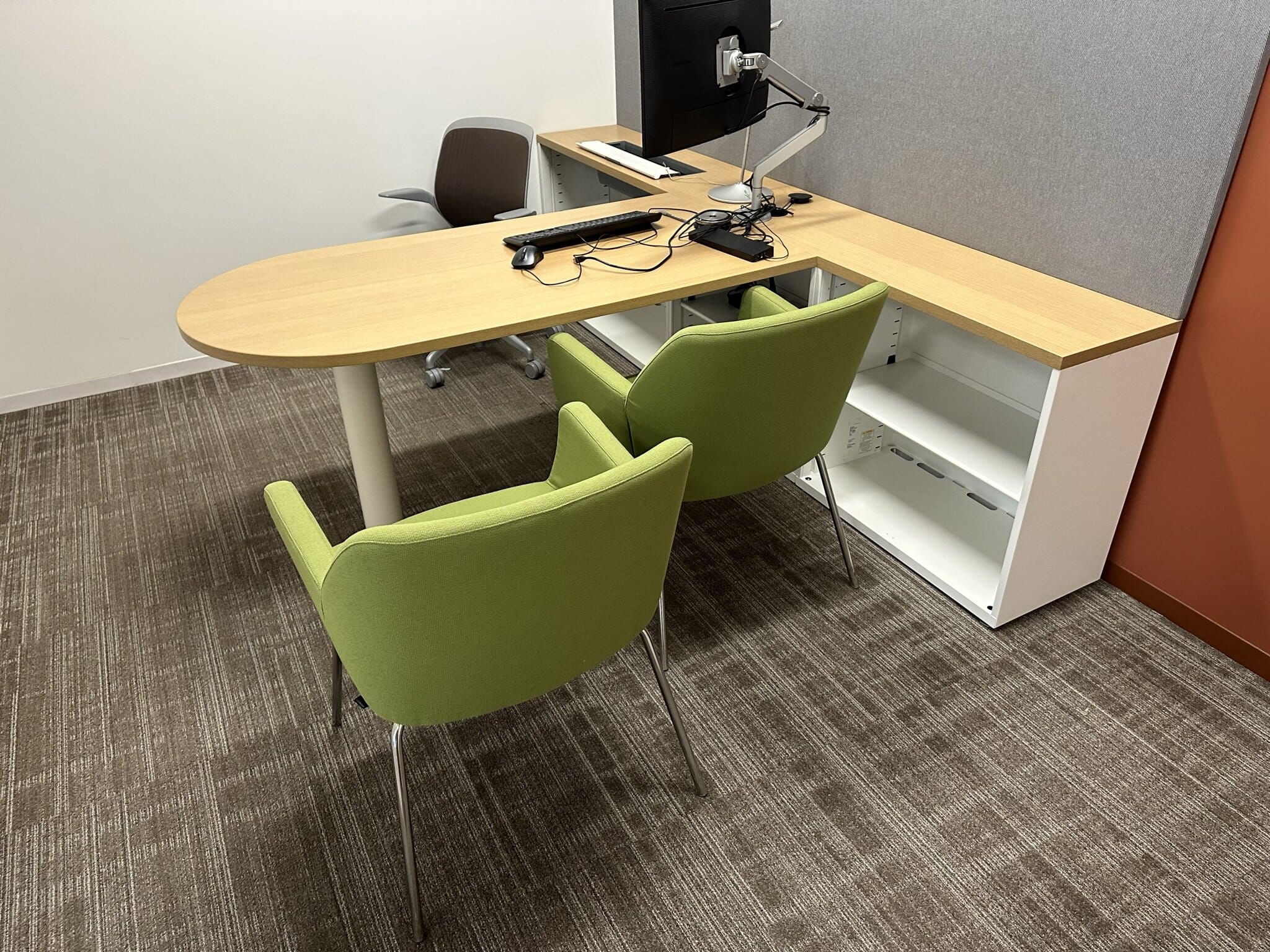 Office desk with computer setup and seating for meetings or consultations.