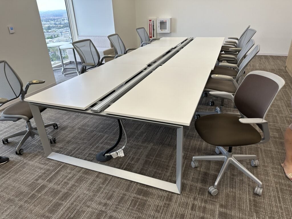 Modern office conference room with ergonomic chairs and adjustable tables.