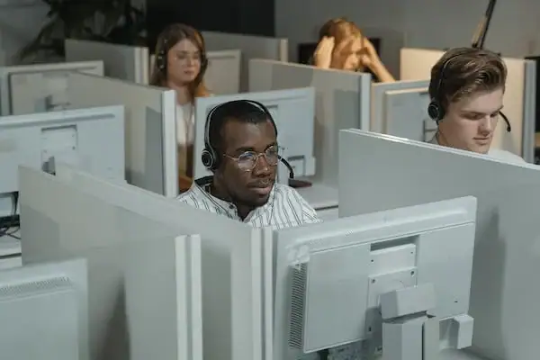 Modern office with multiple workers at ergonomic desks and computers.