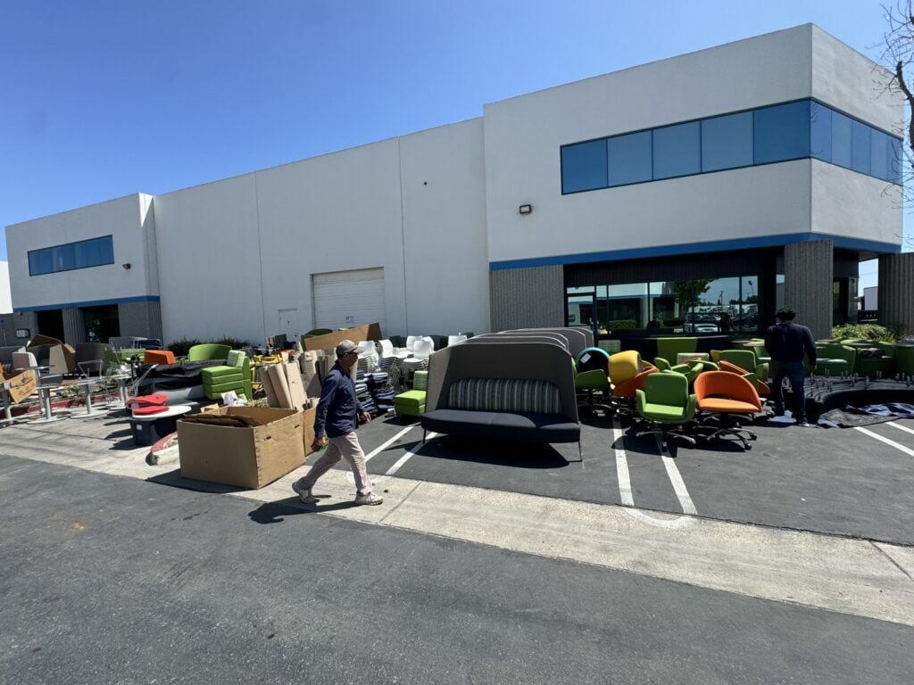 Office furniture and equipment being moved during facility decommission at Cube World USA.