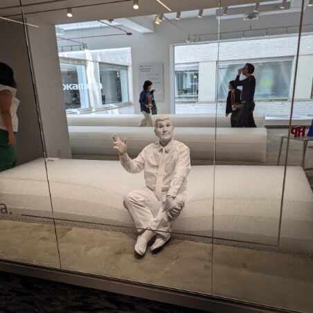 Modern sculpture of a man sitting on a curved bench.