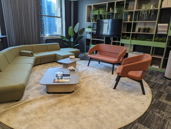 Contemporary office lounge with comfortable chairs, sofa, and lush green accents.