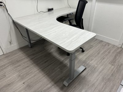 Office furniture liquidation: modern white desk with black ergonomic chair in a clean, minimal works.