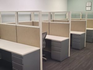 Office cubicles with desks and chairs in a professional workspace setting.